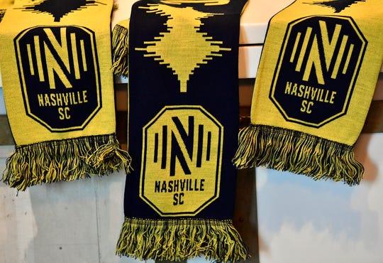 The scarves are resting on a shelf with the new logo of the Nashville MLS franchise and the team's name at Marathon Music Works on Wednesday, February 20, 2019 in Nashville, Tennessee.