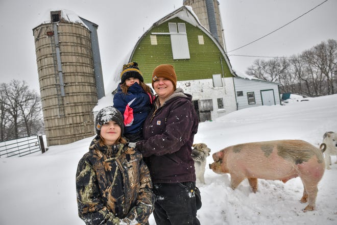 Brenda Rudolph poses for a photograph with her children, Everett and Vivian, and pig, Hans, Wednesday, Feb. 20, on their farm near Little Falls.