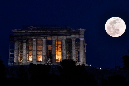 The supermoon rises Tuesday next to the Parthenon temple on the archaeological site of the Acropolis.