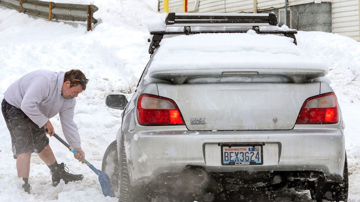 An unidentified motorist works to get his stuck car out of his driveway on Wednesday, Feb. 13, 2019, during a snow storm in Pullman, Wash. (Geoff Crimmins/The Moscow-Pullman Daily News via AP)