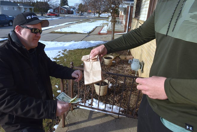 Mr. Nice Guys Caregivers managing member Phil Russo, left, 40, delivers 1/8th-ounce of indica medical marijuana in a 'dab' container to customer Jeff (no last name given) at his Macomb County residence. Jeff uses medical marijuana to control pain after back surgery.
