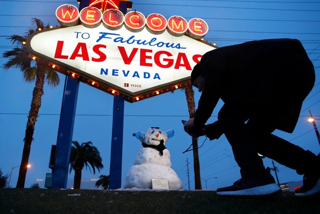 A man, who declined to give his name, takes a picture of a small snowman at the "Welcome to Fabulous Las Vegas" sign along the Las Vegas Strip, Thursday, Feb. 21, 2019, in Las Vegas.