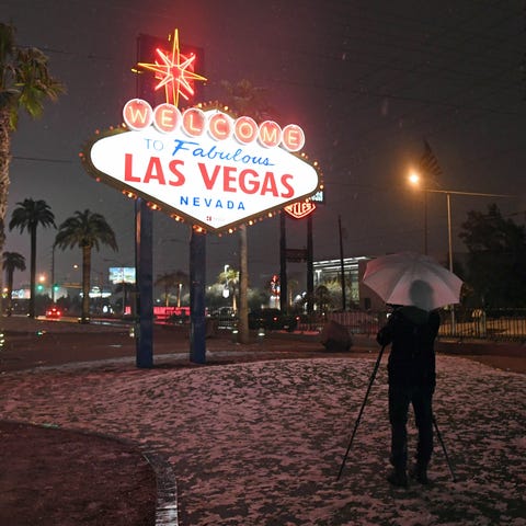 A photographer uses an umbrella to protect his...