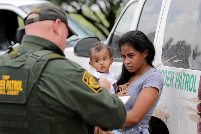 A mother migrating from Honduras holds her 1-year-old child while surrendering to U.S. Border Patrol agents after illegally crossing the border near McAllen, Texas, on June 25, 2018.
