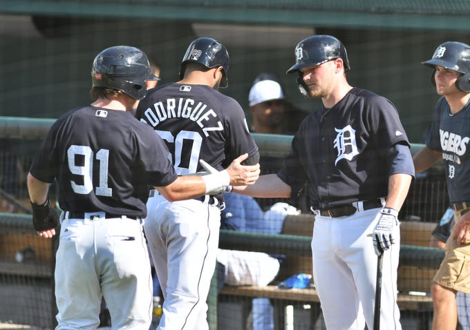 Tigers minor leaguer Kody Eaves congratulates Troy Montgomery (91) and Ronny Rodriguez after they score on a triple by Brady Policelli in the eighth inning.