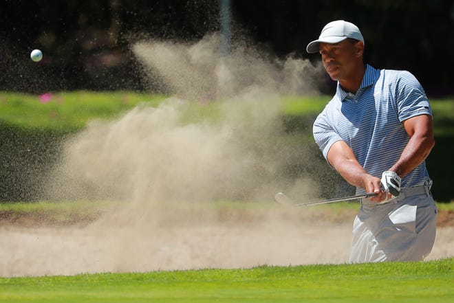 Tiger Woods hits out of a bunker during Thursday's first round.