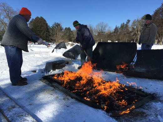 Kris Bloedow (from left), Bill Jessen and Ben Bloedow light a bed of charcoal that will burn overnight and thaw the ground at a grave in Avoca Cemetery. They will dig the grave by hand the following day. Frost at the cemetery, located in Iowa County near the Wisconsin River, was about 20 inches deep.