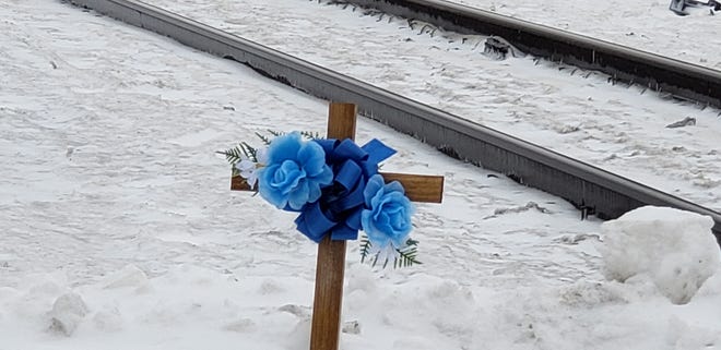 On a snow pile, rests a wooden cross adorned with silk blue roses and ribbons in memory of Michael  "Mike" J. Hayden, 70, of Brookfield who was killed in a train crash on Feb. 18.