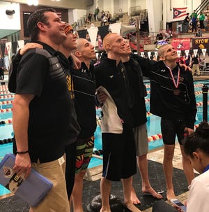 Lexington coach Brock Spurling, along with swimmers Justice Holmes, Wilson Cannon, Connor Miller, Cayman Eichler and Jamin Howe pose for fans taking pictures from high in the stands after the Minutemen make program history by finishing third in the Division II boys standings at the state meet.