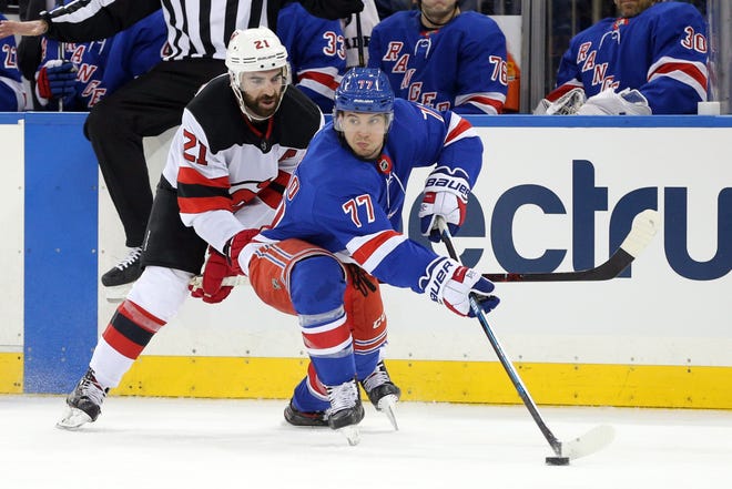 Feb 23, 2019; New York, NY, USA; New York Rangers defenseman Tony DeAngelo (77) plays the puck against New Jersey Devils right wing Kyle Palmieri (21) during the third period at Madison Square Garden.