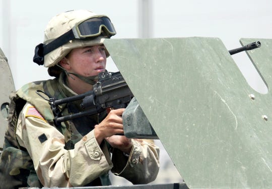 A female soldier mans a machine gun on a vehicle during clashes in the northern Iraqi city of Mosul in 2003. A federal judge in Texas has ruled that now that combat roles are available to women, a male-only draft is unconstitutional.