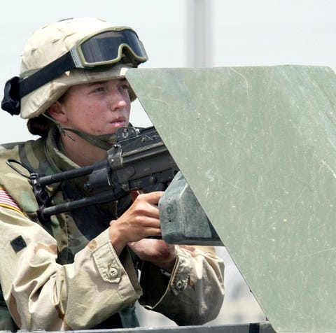 A female soldier mans a machine gun on a vehicle...