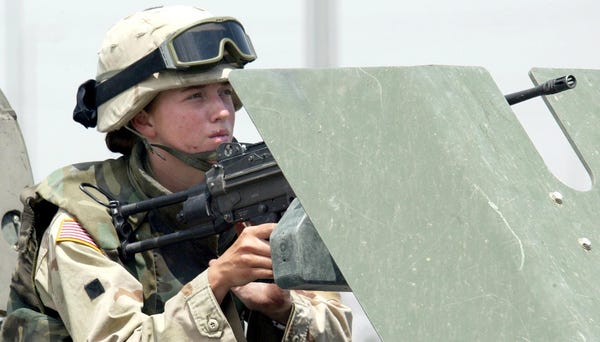A female soldier mans a machine gun on a vehicle...