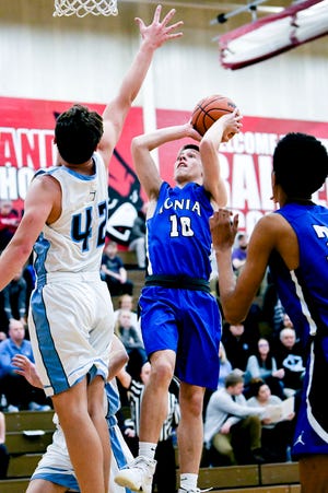 Ionia's Nick Szymanski, right, makes a basket and is fouled as Lansing Catholic's Charlie Nylander, left, defends during a Division 2 district opener in February. The MHSAA Representative Council approved seeding at he district level of the state tournament for next school year.