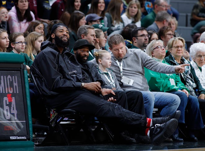 Detroit Pistons center Andre Drummond, left, watches from courtside during an NCAA college basketball game between Michigan and Michigan State, Sunday, Feb. 24, 2019, in East Lansing, Mich. Michigan State won 74-64. (AP Photo/Al Goldis)