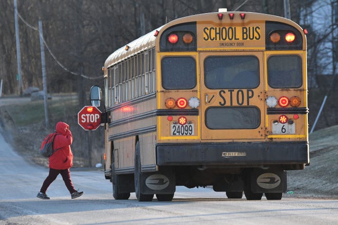 A student crosses the street before boarding an Ontario Schools bus on a chilly Monday morning.