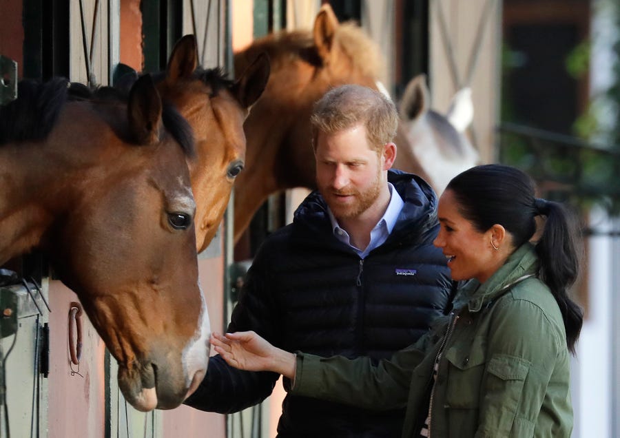 Prince Harry and Duchess Meghan stop to stroke horses in their stables during a visit to the Moroccan Royal Federation of Equestrian Sports in Rabat in Morocco, Feb. 25, 2019.