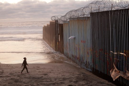 A woman walks on the beach next to a border fence in Tijuana, Mexico on January 9, 2019. President Donald Trump has declared a national emergency to secure billions of dollars in order to build more barriers along the way. the US-Mexico border and the democrats are trying to end the declaration.