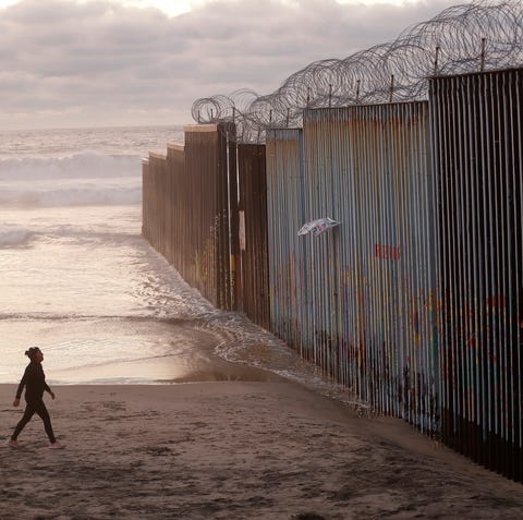 A woman walks on the beach next to a border...