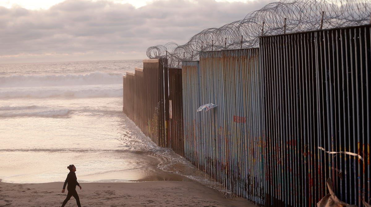 A woman walks on the beach next to a border barrier in Tijuana, Mexico Jan. 9, 2019. President Donald Trump has declared a national emergency to secure billions of dollars to build more barrier along the U.S.-Mexico border and Democrats are trying to halt the declaration.