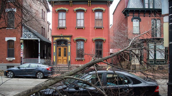 A tree downed by strong winds lays across the...