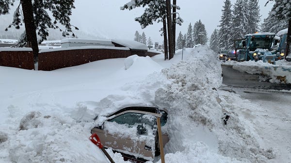 The pried open door of a vehicle fully buried in...