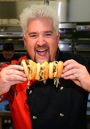 Chef and television personality Guy Fieri holds hamburgers in the kitchen during a welcome event for Guy Fieri's Vegas Kitchen & Bar at The Quad Resort & Casino in Las Vegas, Nevada.