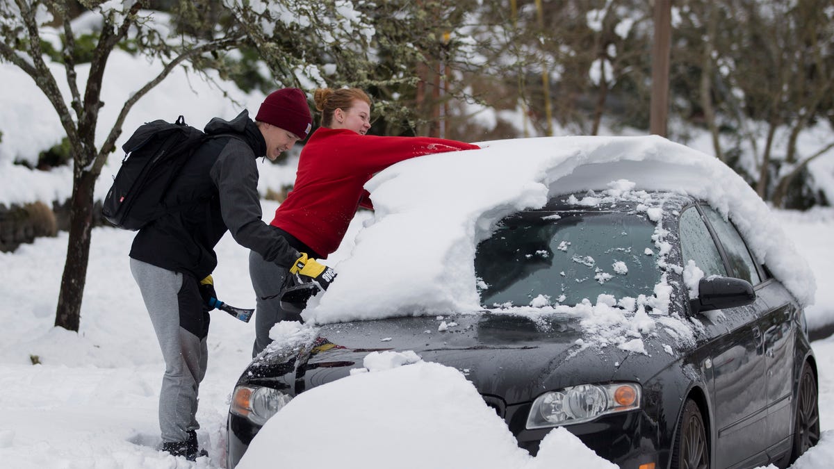 University of Oregon students Trent Ward and Mollie Herron work to clear snow from Ward's car parked in Eugene, Ore.