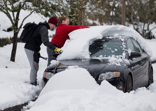 University of Oregon students Trent Ward and Mollie Herron work to clear snow from Ward's car parked in Eugene, Ore.