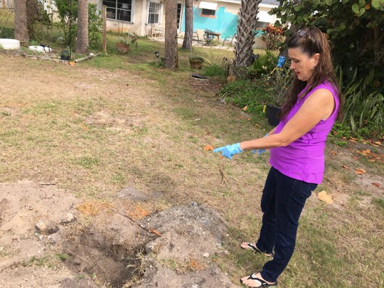 Sandra Sullivan, of South Patrick Shores, points to a hole in her yard where EPA sampling was halted because debris was found. Sullivan said the EPA unearthed a variety of debris, including what looked like a military green piece of airplane aluminum.