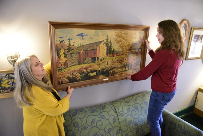 Kathy Fetzer-Goodwin, left, and Llalan Fowler hang an entry to the Monster Painting exhibit at Main Street Books.