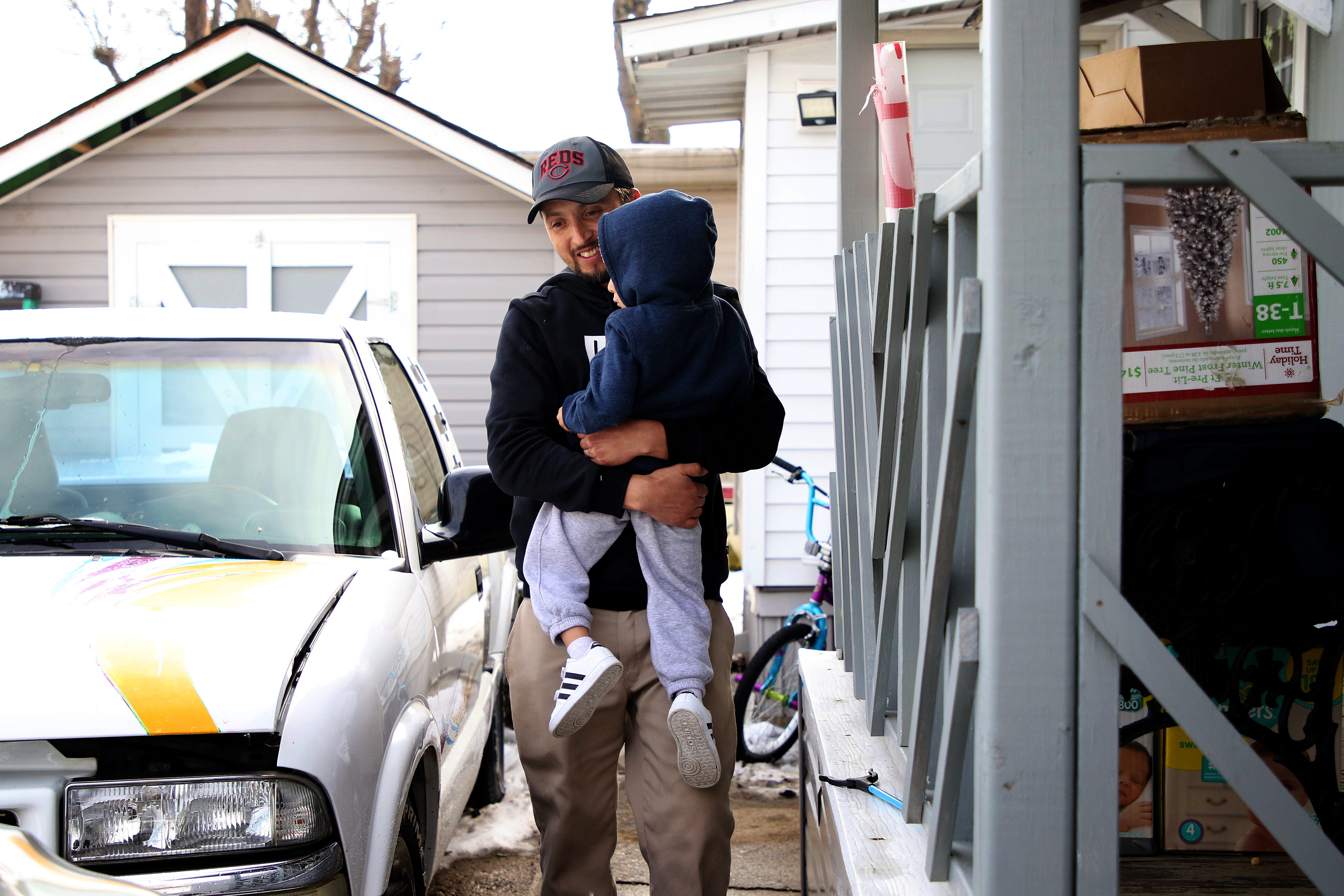Franciso Ramirez carries his 3-year-old son, Roberto, across the driveway from their single-wide trailer. A growing hostility toward immigrants like Ramirez has him fearful his family of six will be deported.