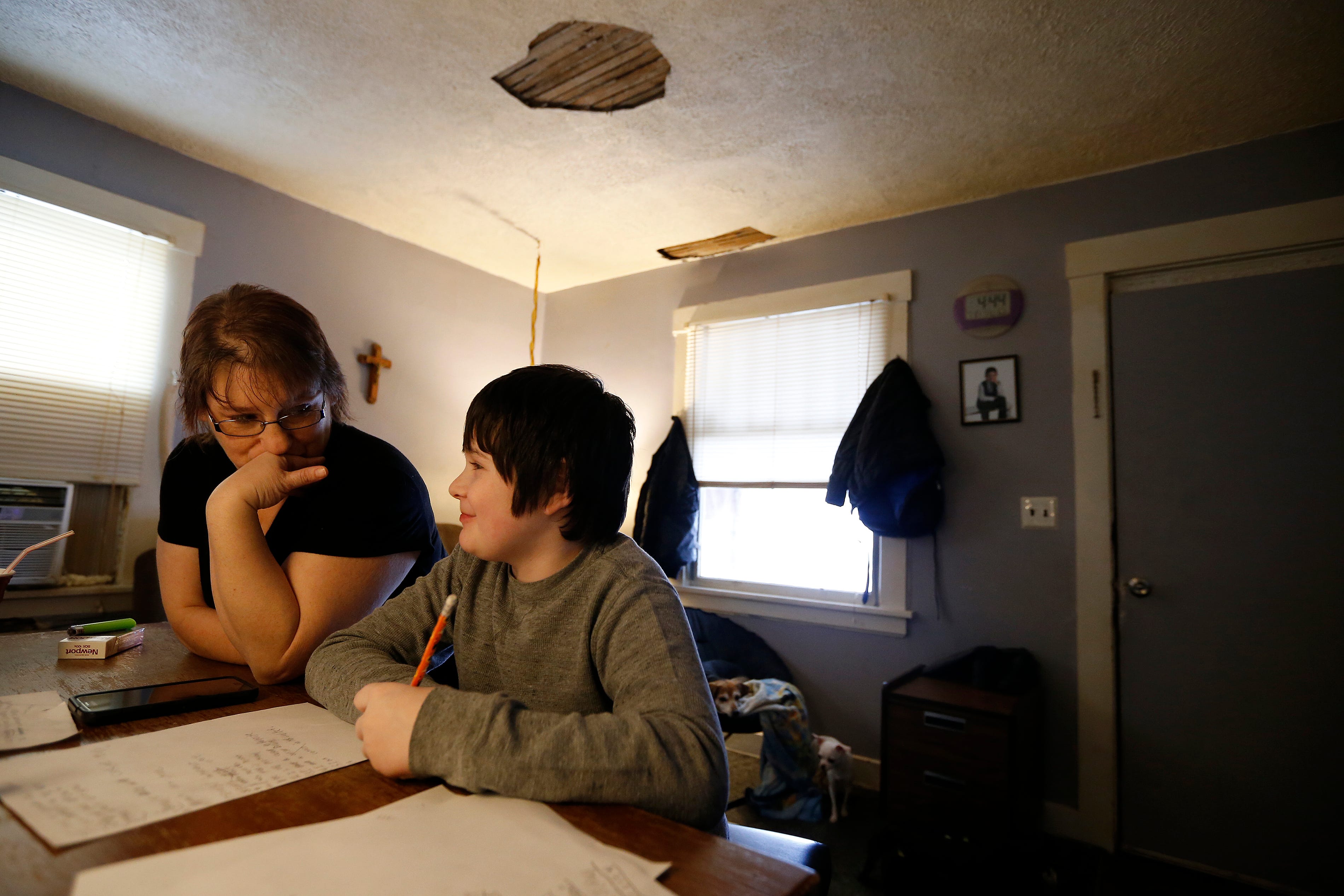 Ten-year-old Bryan Barrett Jr. gets some help with his spelling work from Mandy Williamson, his father's girlfriend. Bryan's family can't afford an annual checkup for the boy.