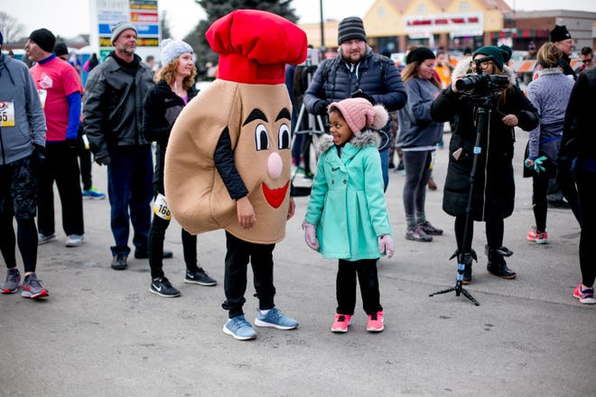 Emily Gilchrist looks at a person dressed as a paczki at the 7th annual  Paczki Run in Hamtramck on March 2, 2019.