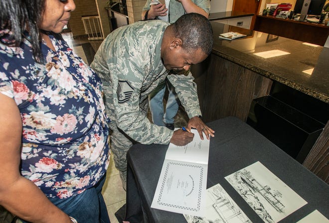 MSgt. Columbus Cook signs a copy of "Marty Makes a Difference," a book he illustrated. Cook donated several pieces of his artwork to Wetumpka on Friday, Feb. 22, 2019.