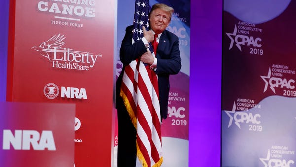 President Donald Trump hugs the American flag as...