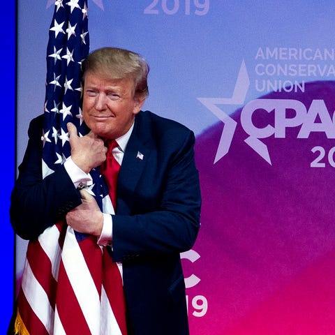 President Donald Trump hugs the American flag as...