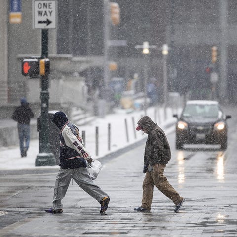 Pedestrians make their way through a bout of Sunda