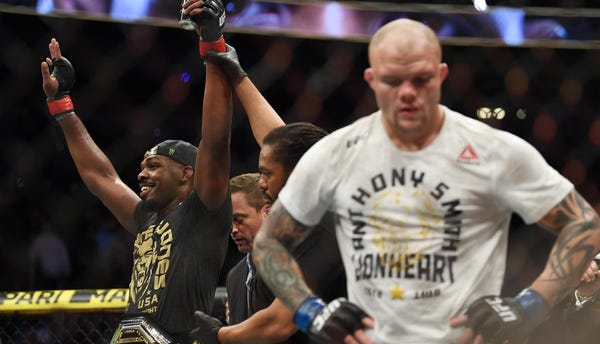 Jon Jones (red gloves) retains his title belt...