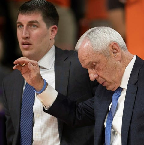 North Carolina coach Roy Williams is escorted off...
