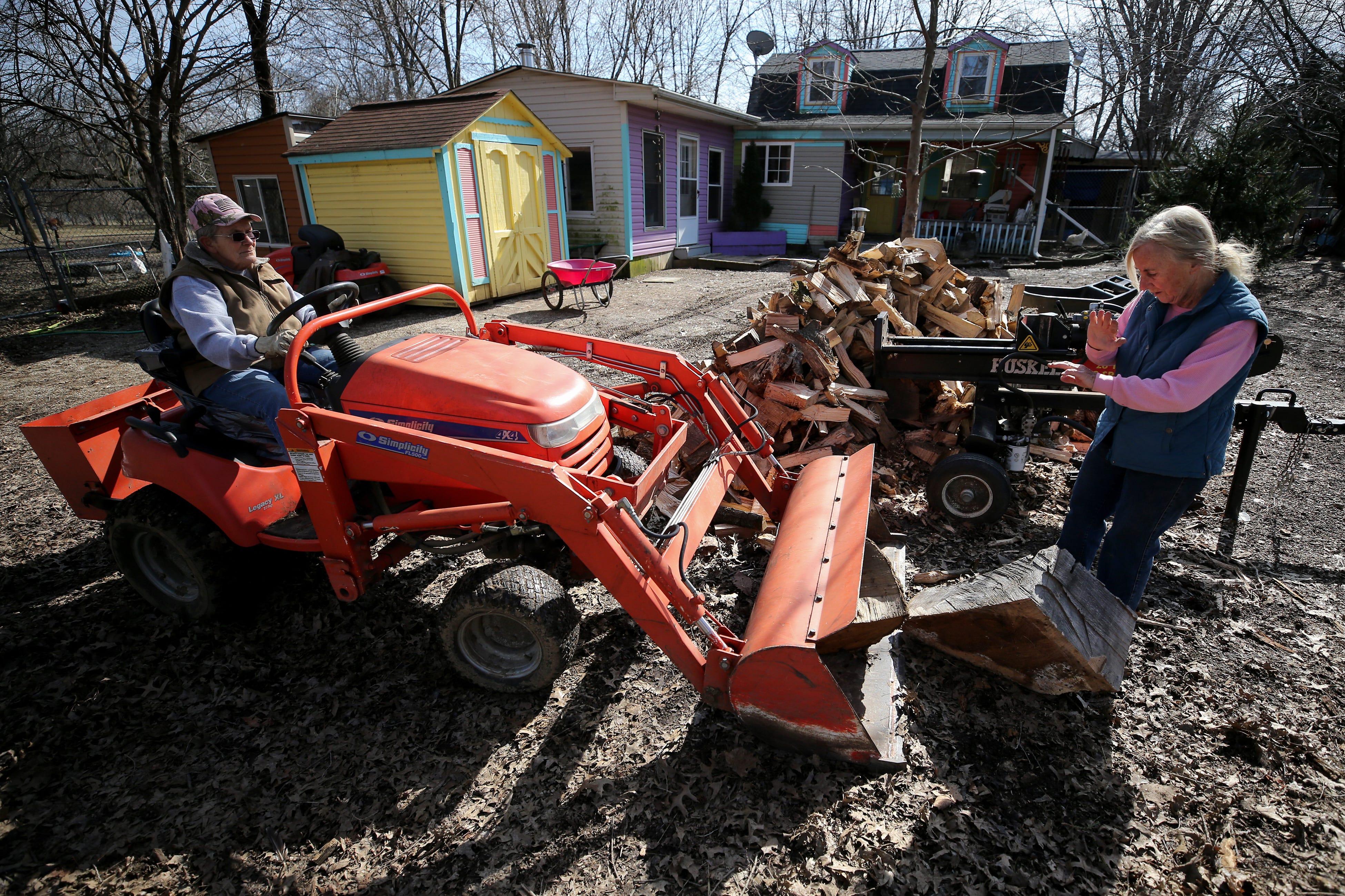 Jane Otterbein and Beverly Skinner unload a tractor of wood to split.