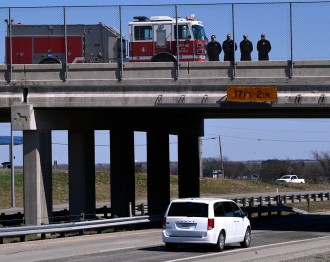 Abilene Fire Department firefighters stand on the West Lake Road overpass over Interstate 20 as the body of slain Midland police officer Nathan Heidelberg was taken Tuesday to Fort Work. Heidelberg had been killed earlier in the day responding to an alarm at a residence, his body was being taken to Tarrant County for an autopsy.