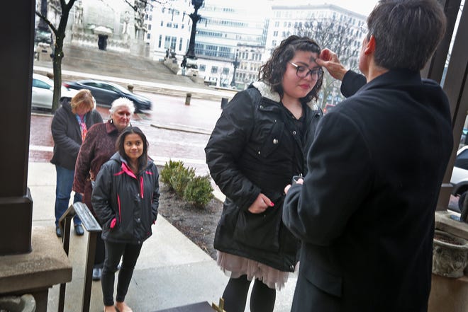 The Rev. Tom Kryder-Reid, right, signs the cross of ashes on the forehead of Siara Reyes, as others wait their turn, on Ash Wednesday "Ashes On The Go!" offered at Christ Church Cathedral on Monument Circle, on Feb. 14, 2018. People could come up to receive the ashes and head on their way.
