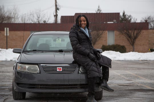 Amanda Hill, 27, poses next to her 2005 Saturn Ion she bought last year in order to avoid car payments. She paid $500 for that car but she's dealing with $90,000 in student loan debt.