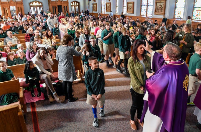 Father Larry McBride conducts the morning, all-school Ash Wednesday Mass at Henderson’s Holy Name of Jesus Catholic Church Wednesday for students, staff and families from Holy Name School.