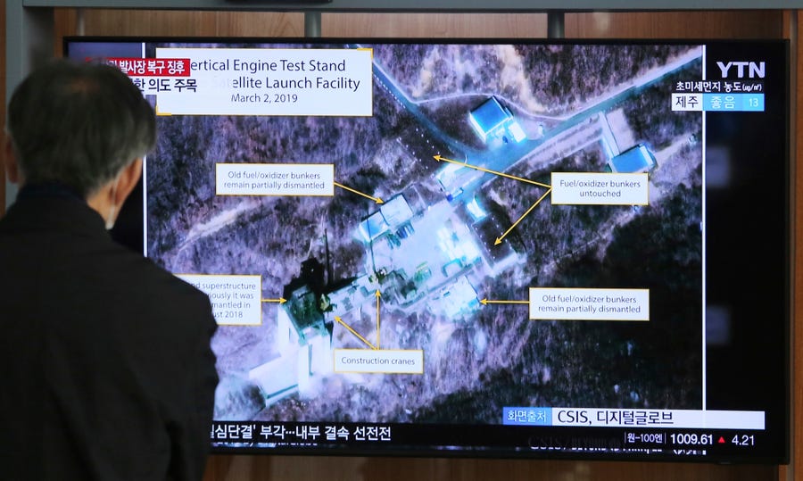 A man watches a TV screen showing a satellite launching facility in North Korea.