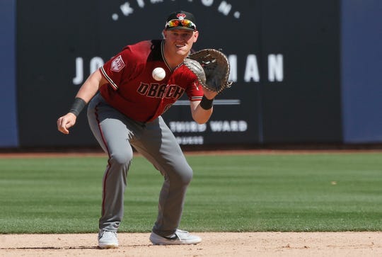 Arizona Diamondbacks first baseman Kevin Cron fields a ground ball hit by Milwaukee Brewers' Corey Ray in the seventh inning of a spring training baseball game Friday, March 8, 2019, in Phoenix.