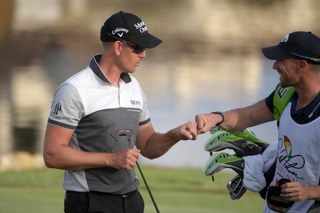 Henrik Stenson, left, gets a fist bump from his caddie after making a putt on the 18th green.