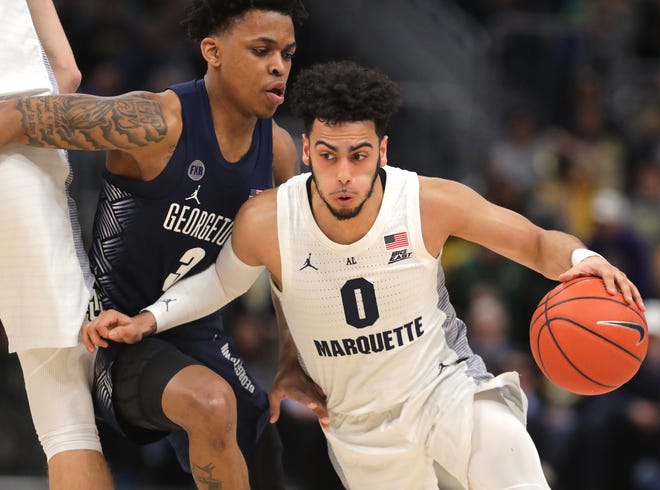 Marquette guard Markus Howard uses his arm and gets past Georgetown guard James Akinjo.