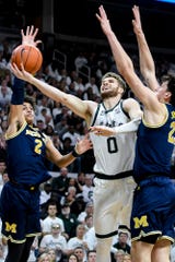 Kyle Ahrens, of central Michigan State, creates a basket between Jordan Poole (Michigan, left) and Brandon Johns Jr. during the first half, Saturday, March 9, 2019, at the Breslin Center, in East Lansing.